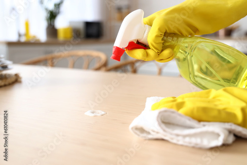 Housewife cleaning dining table in kitchen, closeup