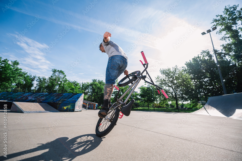 Obraz premium A professional mature bmx bike rider is practicing tricks in a skate park.