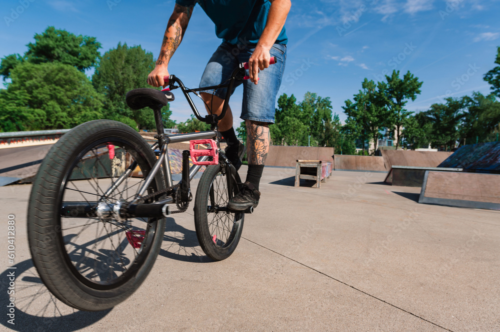 Obraz premium Cropped picture of a tattooed man doing a 360 rotation on his bmx in a skate park.