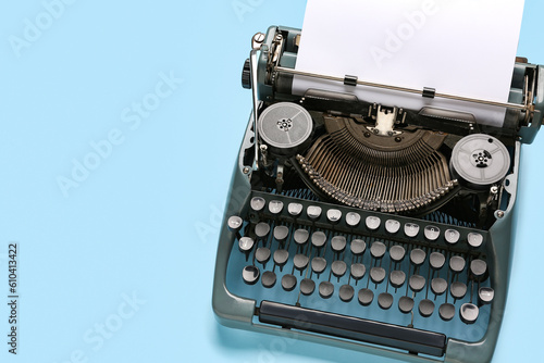 Vintage typewriter with blank paper sheet on blue background