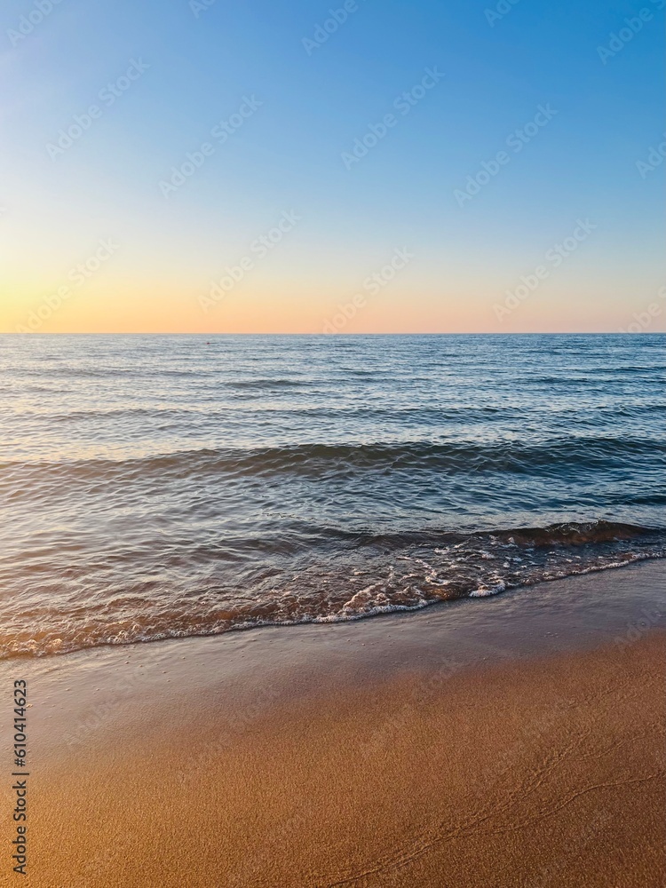 Evening sea coast, sandy sea coastline, evening sea horizon, blue clear sky with some sunlight
