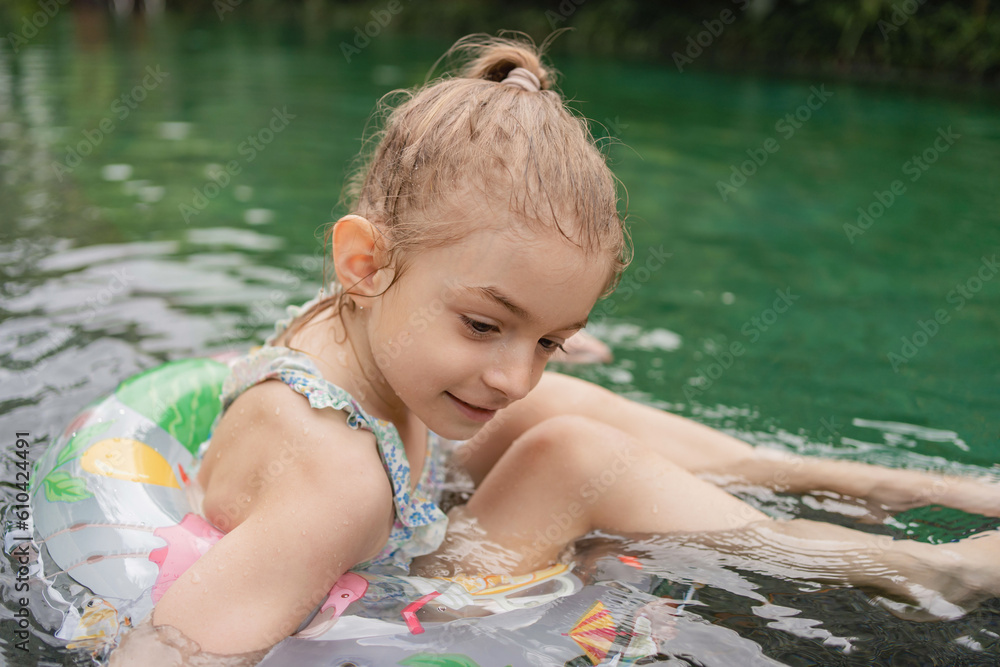 Child with inflatable toy ring float in swimming pool. Little girl ...