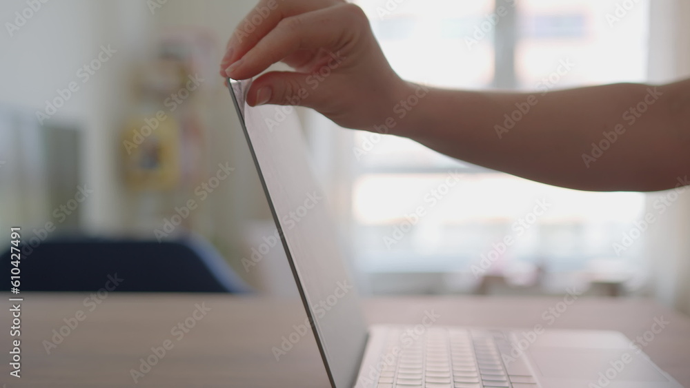 Removing protective film from monitor of new laptop or notebook. Close up view of girl removing