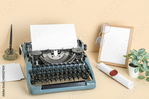 Vintage typewriter, empty frame, eyeglasses and scroll with wax seal stamp on beige background