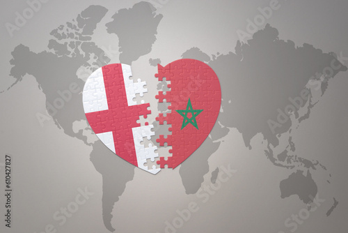 puzzle heart with the national flag of morocco and england on a world map background.Concept.