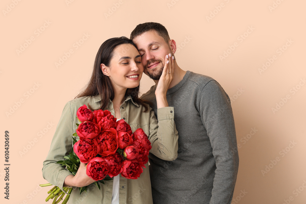 Happy engaged couple with flowers on beige background Happy engaged couple with flowers on beige background