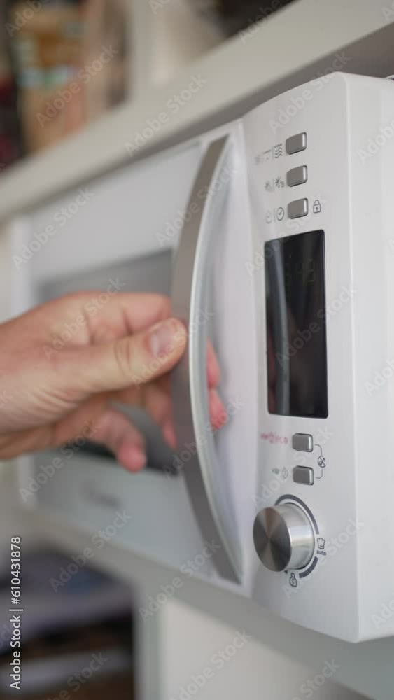 Vertical video of an unrecognizable man's hand picking up his freshly heated cup of tea or coffee from the microwave. Vertical video of an unrecognizable man's hand picking up his freshly heated cup of tea or coffee from the microwave.