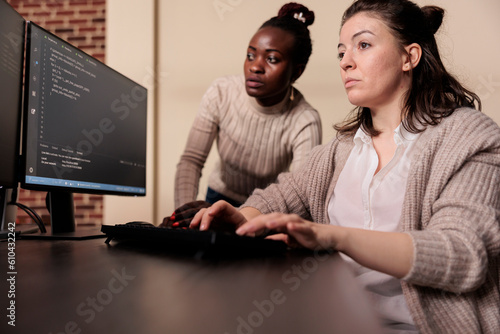 Diverse team of tech enginners talking about programming in it development agency. African american programmer compiling app language with software developer, innovating online server algorithms. photo