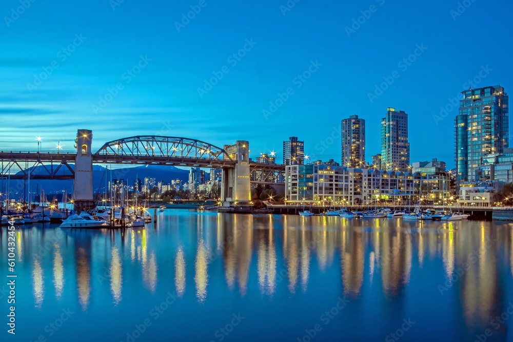 Vancouver Canada, Burrard Bridge and downtown Vancouver at night, reflection of the city's night lights in the mirror water of the bay, shot done from Granville Island