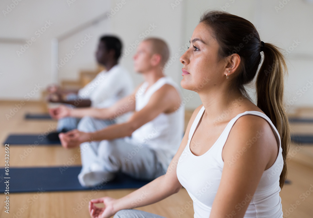Group of man and woman making yoga meditation in lotus pose at gym