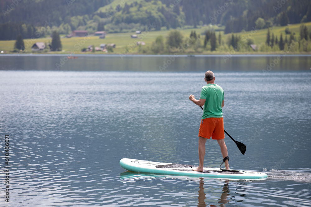 Middleaged man standing on a surfboard on a lake Middleaged man standing on a surfboard on a lake
