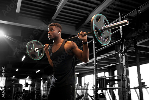 Konstfotografi african american man lifts barbell in dark gym, sports guy trains in fitness roo