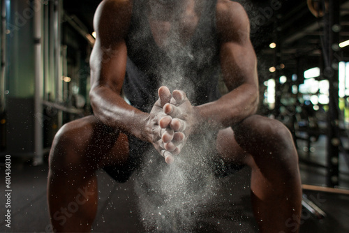 Принти на полотні sporty african american man trains in dark gym and rubs his hands with magnesia,