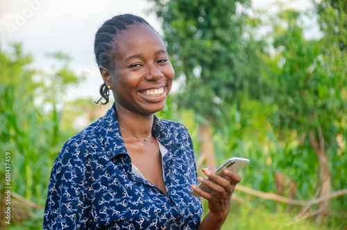 female african farmer using her phone. african farmer checks her mobile phone, texts and chat