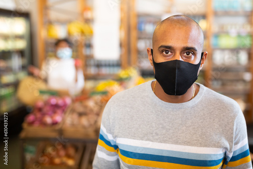 Man in protective mask with basket at grocery store