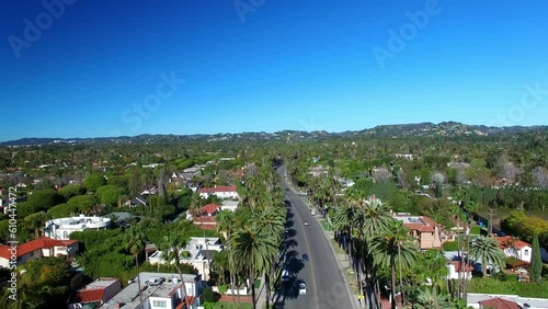 Aerial Shot Of Vehicles On Road Amidst Trees Against Sky, Drone Ascending Forward Over Houses In Suburb On Sunny Day - Beverly Hills, California