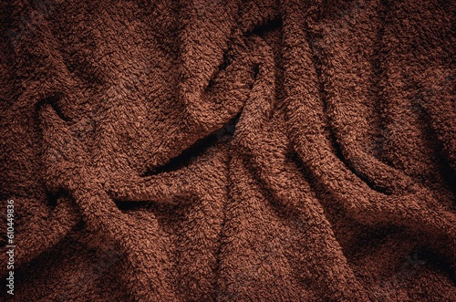 Furry wrinkled blanket texture. Close-up of brown material, may be used as background.