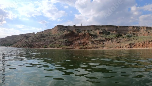 View of coast land shore beach from sea from ship. Sunny summer day. Mountain hill on coast. Floating sail on ship. Sailing on boat vessel. Seascape sea view landscape. Waterscape scenery. Slow motion photo