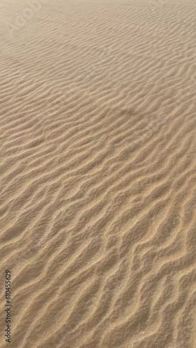 Sand moving over dunes in windy desert weather. 
