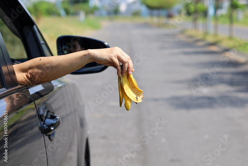 Woman's arm throws fruit waste from car window.  bad behavior of car drivers throwing garbage on the road photo