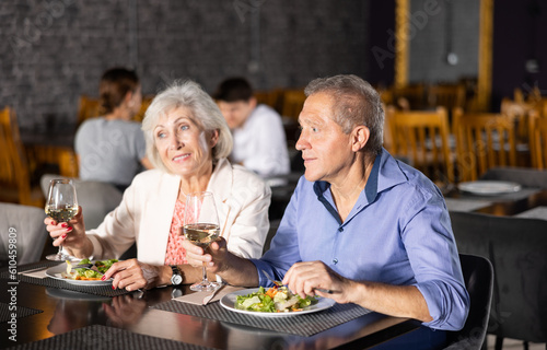 Couple of elderly man and woman having dinner and drinking wine together in restaurant