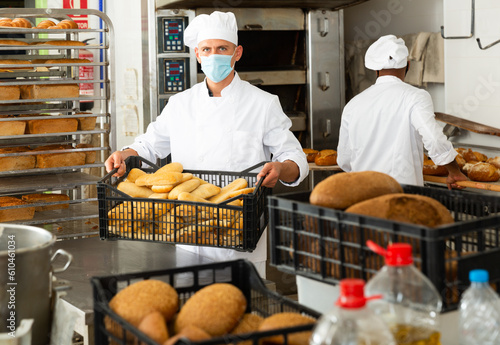 Portrait of baker in protective mask with fresh bread at the bakery