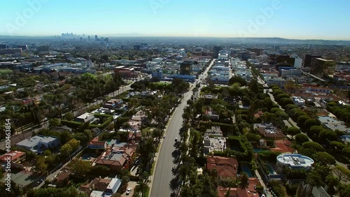 Aerial Shot Of Vehicles On Street Amidst Buildings Against Sky, Drone Flying Forward Over Suburb In City On Sunny Day - Beverly Hills, California