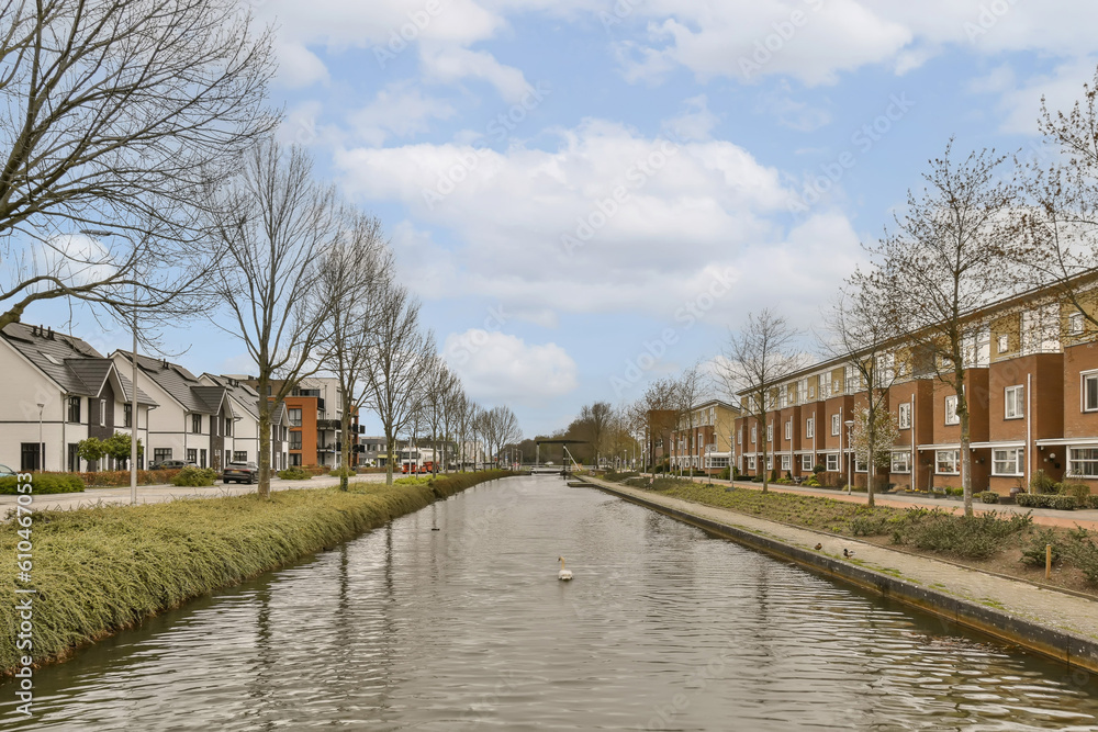 a canal in the middle of a residential area with houses on both sides and trees lining the side of the river