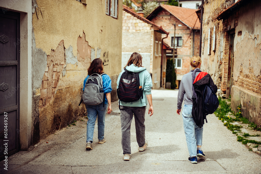 Three female friends of the traveler are walking through the narrow streets of the old European city. Hiking in historical places of the world