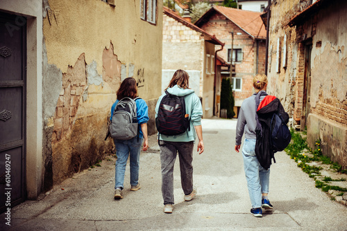 Three female friends of the traveler are walking through the narrow streets of the old European city. Hiking in historical places of the world © Kate Stock