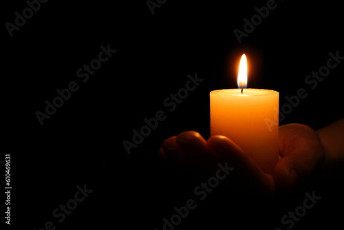 Woman holding burning candle in hand on black background, closeup. Space for text