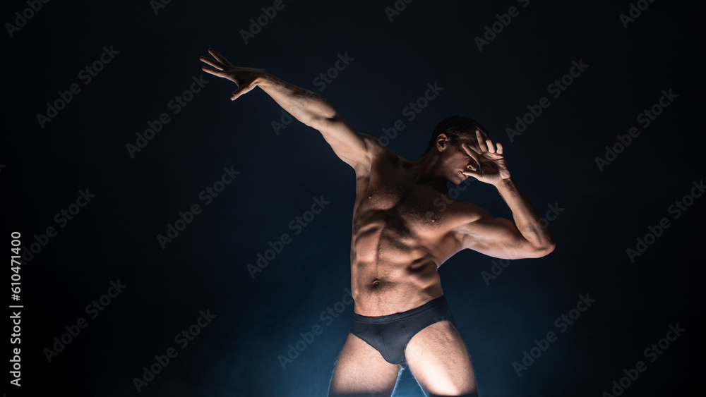 Muscular athlete in an epic pose, dark background, bright light from below, the concept of sports and bodybuilding Muscular athlete in an epic pose, dark background, bright light from below, the concept of sports and bodybuilding