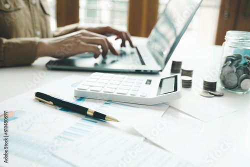 Woman accountant working on laptop computer while counting taxes online.