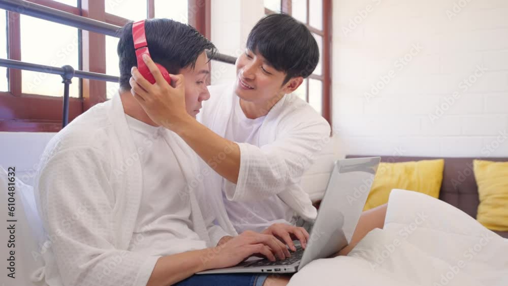 Asian attractive gay couple using laptop watching movie in bedroom. Asian attractive gay couple using laptop watching movie in bedroom.