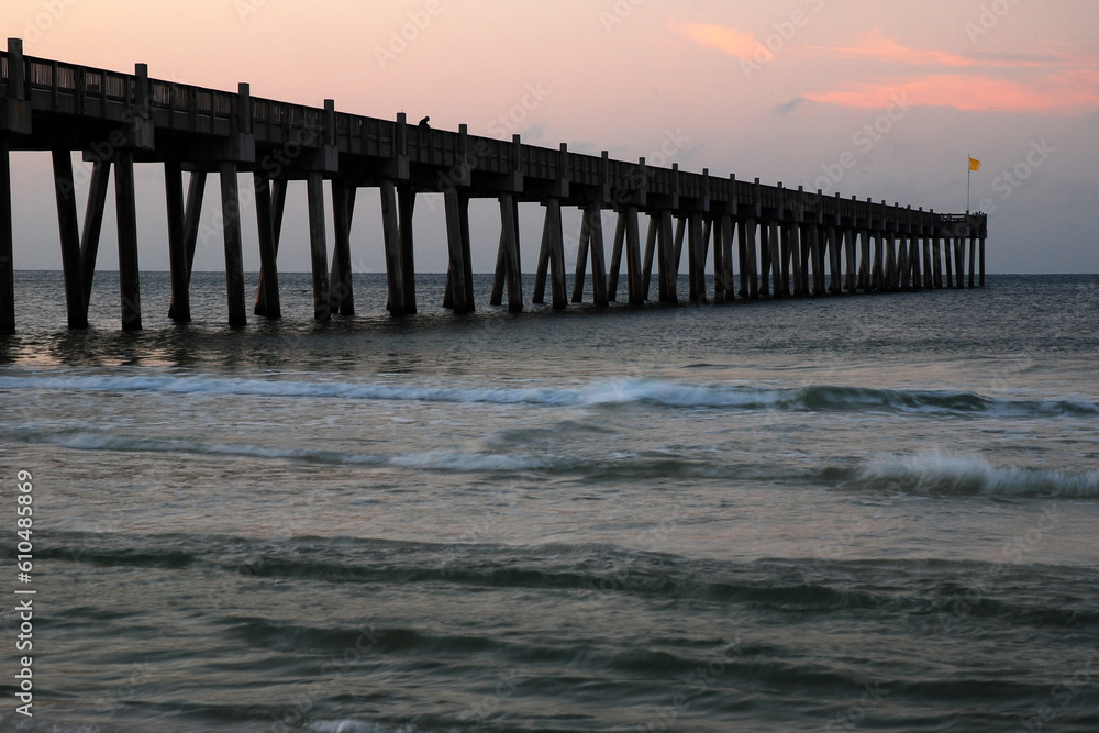 The Pensacola Pier juts out into the ocean and gulf from the beach during sunrise