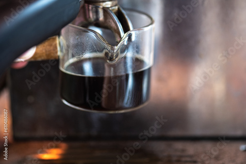 Close up of a glass cup with shot of espresso on a coffee machine