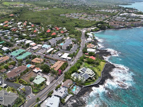 View of coastal Kailua-Kona on the Big Island of Hawai'i. Aerial drone shot along the coast with palm trees, Condominiums, coastal highway, and blue and green waters with volcanic rock. photo