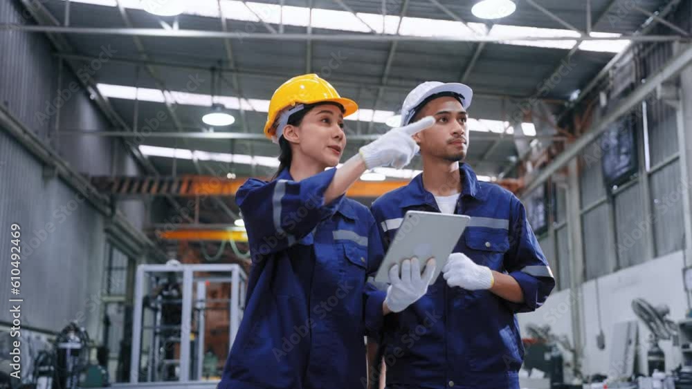 Smart engineer worker man and woman in uniform safety and wear helmet consulting and using tablet help analyze data in warehouse at manufactory.Industrial and factory warehouse concept Smart engineer worker man and woman in uniform safety and wear helmet consulting and using tablet help analyze data in warehouse at manufactory.Industrial and factory warehouse concept