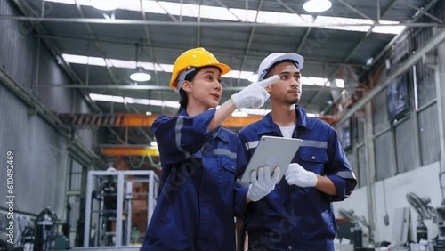 Smart engineer worker man and woman in uniform safety and wear helmet consulting and using tablet help analyze data in warehouse at manufactory.Industrial and factory warehouse concept