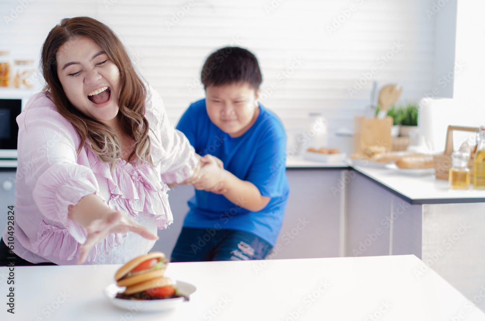 Fat son pulled the fat mother's arm to stop eating, examples of bad eating habits, selective focus