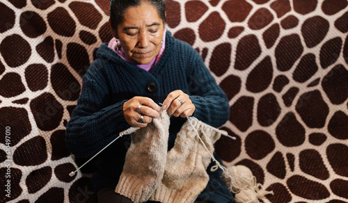 Abuela en la sala de casa feliz y concentrada, usando unos palitos de tejer y lana de oveja, concepto de vida cotidiana tradicional, tejedora tradicional, enfoque selectivo. Dia de los abuelos.