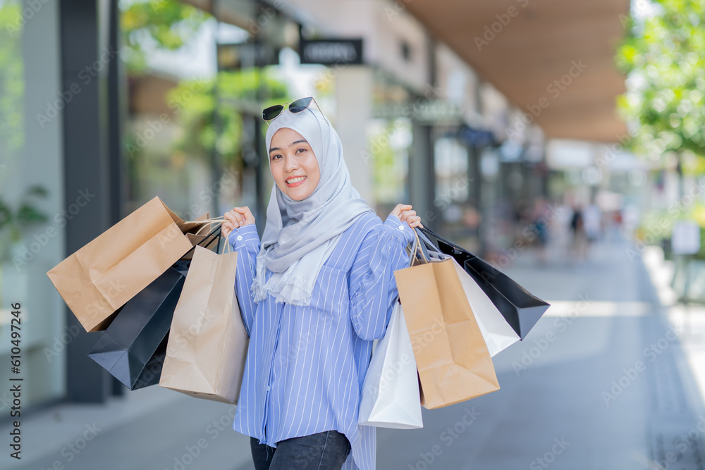 An Asian Muslim woman is carrying a bag of goods that she has been shopping for and buying a lot of products with happy, happy faces. An Asian Muslim woman is carrying a bag of goods that she has been shopping for and buying a lot of products with happy, happy faces.
