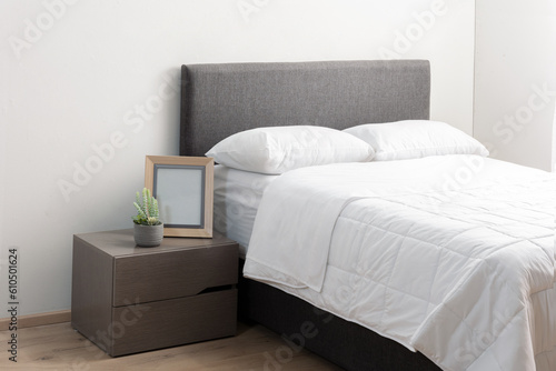 A queen-sized bed in a room featuring a wooden floor and white bedding photo