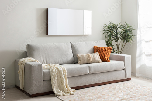 A cozy living room with a plush  beige sofa and two matching pillows situated near a window