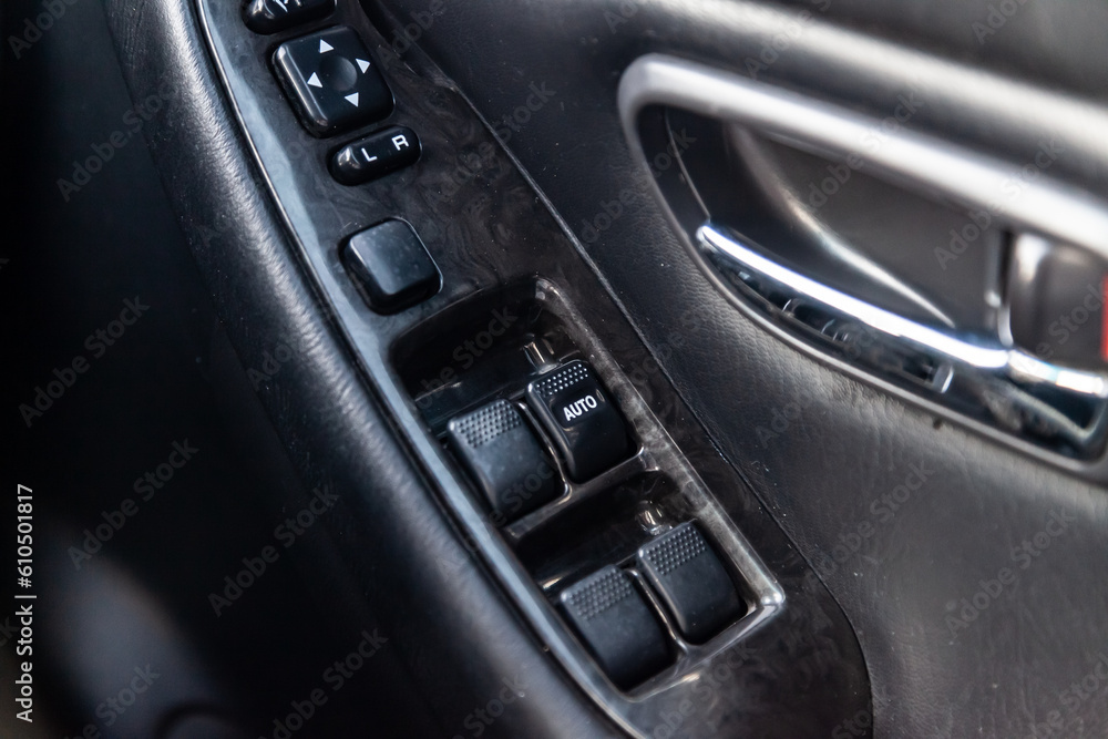 Close-up of the side door buttons: window adjustment buttons, door lock. Window control panel in a modern car. Automatic car window controls and details. Selective focus