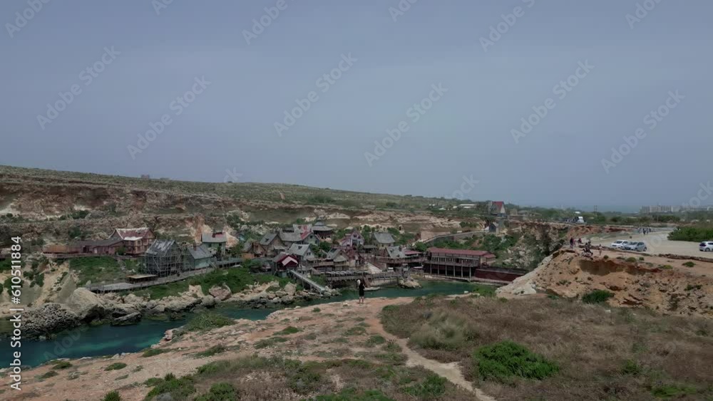 Popeye Village, Mellieha, Malta - Aerial drone forward moving shot over Popeye Village houses in Anchor Bay area, Mellieha, Malta on a sunny day. Popeye Village, Mellieha, Malta - Aerial drone forward moving shot over Popeye Village houses in Anchor Bay area, Mellieha, Malta on a sunny day.