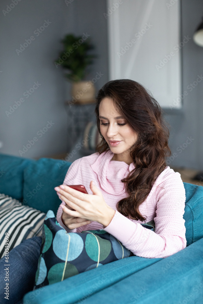 Smiling woman is using the phone on the sofa Smiling woman is using the phone on the sofa