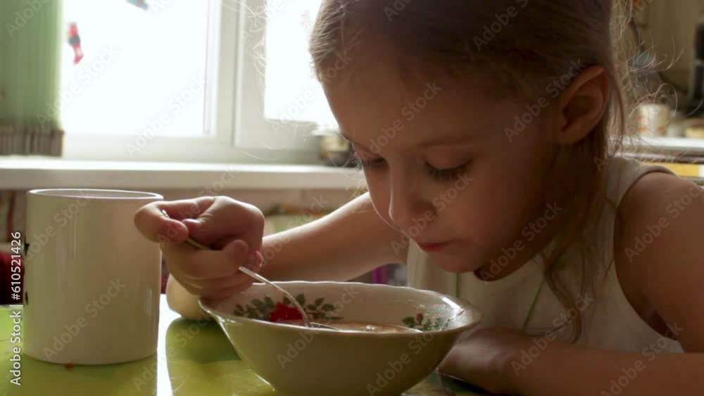 A cute six year old girl is sitting at the table at home and eating soup. Lunch concept. Close-up. Video A cute six year old girl is sitting at the table at home and eating soup. Lunch concept. Close-up. Video