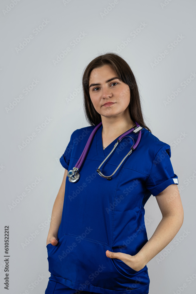 Portrait of woman medical student or doctor in blue uniform with stethoscope isolated on grey Portrait of woman medical student or doctor in blue uniform with stethoscope isolated on grey
