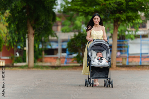 Foto happy mother pushing infant baby stroller and walking in park